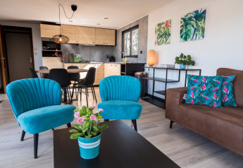 Zona living moderna nei Luxe Lodges di Arden Parks Tulderheyde, Belgio, con poltrone blu vivaci.