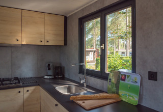Cucina moderna in lodge con mobili in legno, vista verde dalla finestra e baguette sul piano di lavoro.