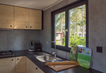 Cuisine moderne de lodge avec placards en bois, fenêtre donnant sur la verdure et baguette sur le plan.
