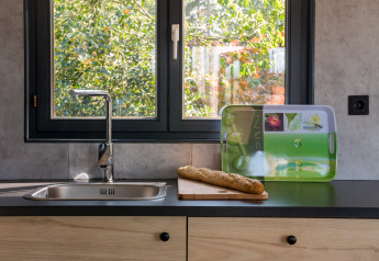 Fregadero moderno con tabla de cortar y baguette frente a la ventana en Luxe Lodges, Arden Parks Tulderheyde, Bélgica.