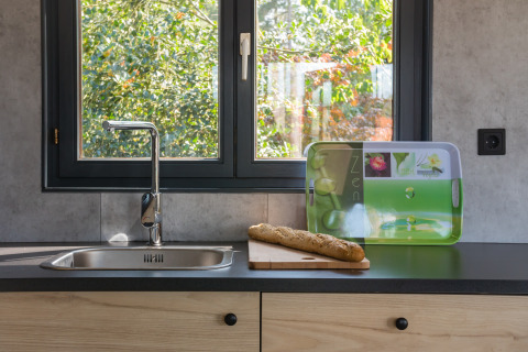 Lavello moderno con baguette su tagliere davanti alla finestra a Luxe Lodges, Arden Parks Tulderheyde, Belgio.