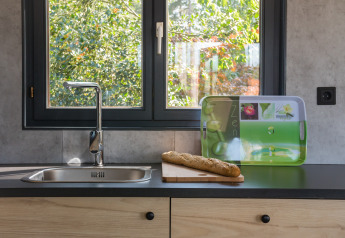 Lavello moderno con baguette su tagliere davanti alla finestra a Luxe Lodges, Arden Parks Tulderheyde, Belgio.
