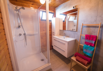 Moderne badkamer met douche, houten muren en kleurrijke handdoeken bij Luxe Lodges in Tulderheyde, België.