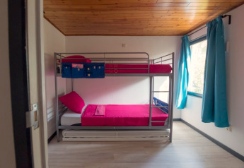 Moderne kamer met stapelbed, rood bedlinnen en blauwe gordijnen bij Luxe Lodges, Arden Parks Tulderheyde, België.