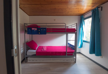 Camera moderna con letto a castello, biancheria rossa e tende blu a Luxe Lodges, Arden Parks Tulderheyde, Belgio.