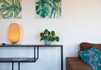 Soggiorno presso Luxe Lodges ad Arden Parks Tulderheyde, Belgio, con decoro tropicale, arte e lampada calda.
