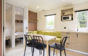 Lyst interiør i Cordelia Lodge, Arden Parks Tulderheyde, Belgien, med spisebord, køkken og soveværelser.
