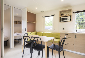 Interno luminoso di Cordelia Lodges ad Arden Parks Tulderheyde, Belgio, con cucina, tavolo e camere da letto.