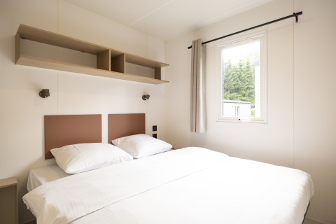 Camera luminosa e moderna ai Cordelia Lodges, Arden Parks Tulderheyde, Belgio, con letto matrimoniale e finestra.