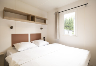 Camera luminosa e moderna ai Cordelia Lodges, Arden Parks Tulderheyde, Belgio, con letto matrimoniale e finestra.