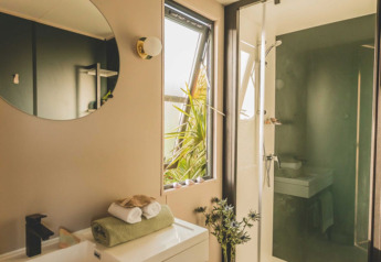 Bagno moderno presso O'Hara Lodge, Arden Parks Tulderheyde, Belgio, con doccia, specchio e piante.
