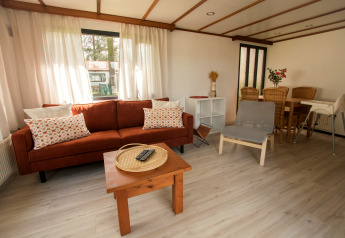 Salon de la Sun Lodge à Arden Parks Tulderheyde en Belgique, avec canapé, fauteuil, coin repas et lumière naturelle.