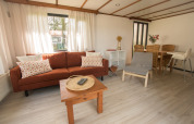 Stue i Sun Lodge ved Arden Parks Tulderheyde, Belgien, med sofagruppe, spisebord og lysindfald.