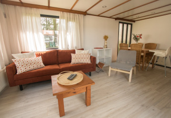 Woonkamer van Sun Lodge in Arden Parks Tulderheyde, België, met zetel, stoel, eettafel en veel daglicht.
