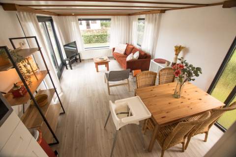 Lichte leefruimte in Sun Lodge, Arden Parks Tulderheyde, België, met eettafel, zetel en veel ramen.
