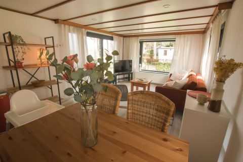 Lichte leefruimte in de Sun Lodge van Arden Parks Tulderheyde, België met houten tafel en zetel.