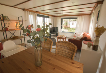Lichte leefruimte in de Sun Lodge van Arden Parks Tulderheyde, België met houten tafel en zetel.