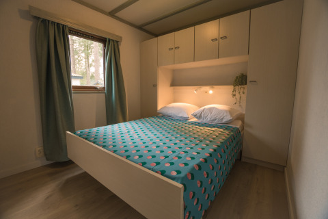 Slaapkamer met dubbel bed en kastruimte in de Sun Lodge van Arden Parks Tulderheyde, België.