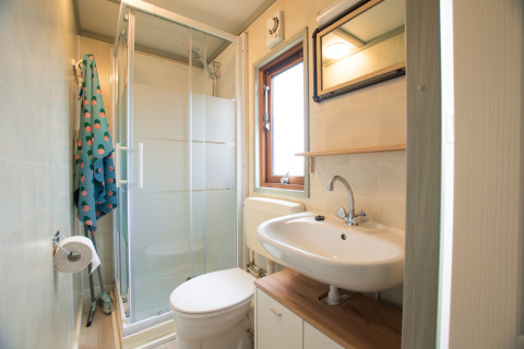 Lichte badkamer in Sun Lodge, Arden Parks Tulderheyde in België, met douche, toilet en wastafel.