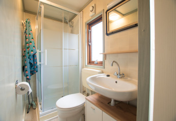 Lichte badkamer in Sun Lodge, Arden Parks Tulderheyde in België, met douche, toilet en wastafel.