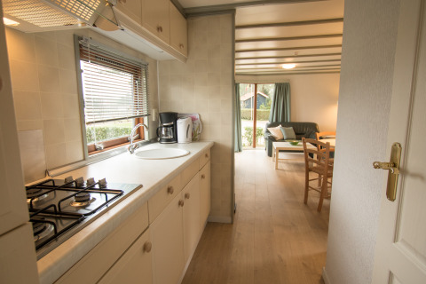 Lichte keuken en zithoek in Sun Lodge te Arden Parks Tulderheyde, België, met ruime ramen en meubilair.