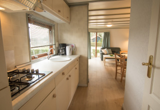 Lichte keuken en zithoek in Sun Lodge te Arden Parks Tulderheyde, België, met ruime ramen en meubilair.