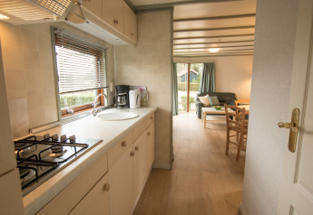 Lichte keuken en zithoek in Sun Lodge te Arden Parks Tulderheyde, België, met ruime ramen en meubilair.