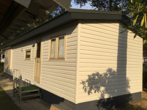 Foto van Sun Lodge bij Arden Parks Tulderheyde in België, beige chalet met ramen en deur te zien.