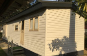 Foto af Sun Lodge ved Arden Parks Tulderheyde i Belgien, viser en beige hytte med vinduer og dør.