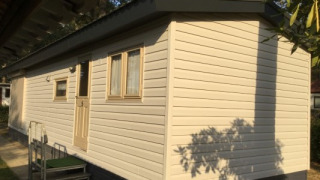 Foto de Sun Lodge en Arden Parks Tulderheyde, Bélgica, mostrando una cabaña beige con ventanas y puerta.