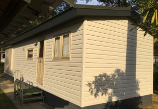 Foto van Sun Lodge bij Arden Parks Tulderheyde in België, beige chalet met ramen en deur te zien.
