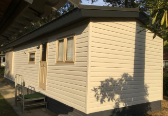 Foto van Sun Lodge bij Arden Parks Tulderheyde in België, beige chalet met ramen en deur te zien.