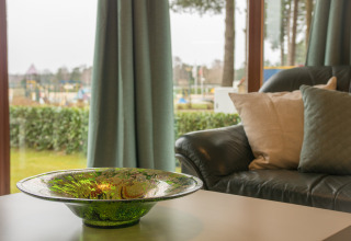 Woonruimte van Sun Lodge in Arden Parks Tulderheyde, België, met groene schaal en uitzicht op de tuin.