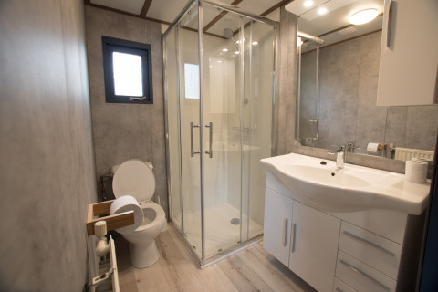 Moderne badkamer in Sun Lodge van Arden Parks Tulderheyde, België, met douche en stijlvol wit meubel.