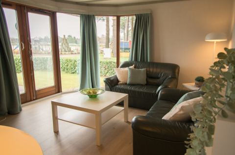 Woonkamer met lederen zetels, salontafel en grote ramen in Sun Lodge, Arden Parks Tulderheyde, België.