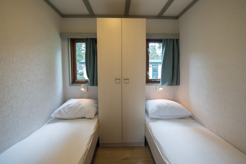 Kleine kamer met twee enkele bedden, een kast in het midden en twee ramen in Sun Lodge, Arden Parks Tulderheyde.