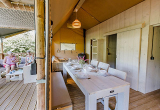 Udendørs spiseområde og opholdsstue i Ranger Lodge ved Arden Parks Tulderheyde, Belgien, med to kvinder.