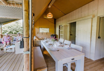Udendørs spiseområde og opholdsstue i Ranger Lodge ved Arden Parks Tulderheyde, Belgien, med to kvinder.