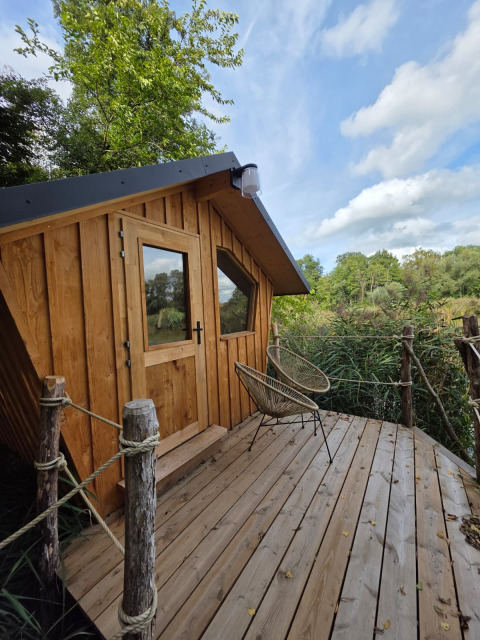Moderne houten glampinghut op een terras omgeven door natuur, ideaal voor een ontspannen uitje.