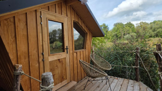 Cabaña de madera moderna para glamping sobre una terraza, rodeada de naturaleza y perfecta para relajarse.