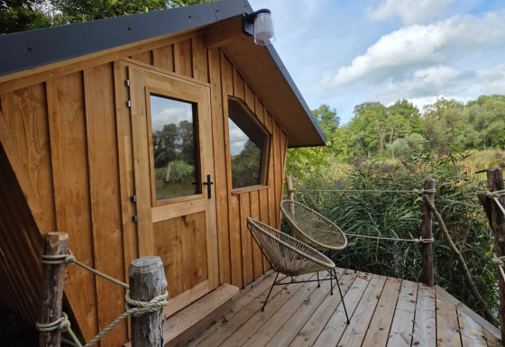 Moderne houten glampinghut op een terras omgeven door natuur, ideaal voor een ontspannen uitje.