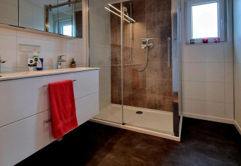 Bagno moderno con doccia in vetro, doppio lavabo e asciugamano rosso al Chalet Enzian, Brilon, Germania.