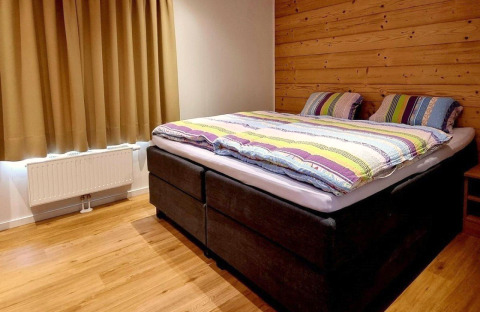 Cozy bedroom at Chalet Enzian in Camping & Ferienpark Brilon, Germany, featuring a double bed and wood wall.
