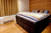Cozy bedroom at Chalet Enzian in Camping & Ferienpark Brilon, Germany, featuring a double bed and wood wall.