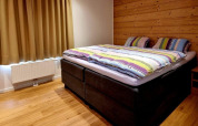 Cozy bedroom at Chalet Enzian in Camping & Ferienpark Brilon, Germany, featuring a double bed and wood wall.