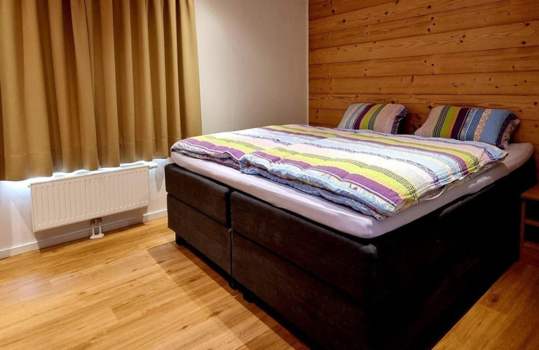 Dormitorio acogedor en Chalet Enzian de Camping & Ferienpark Brilon, Alemania, con cama doble y pared de madera.