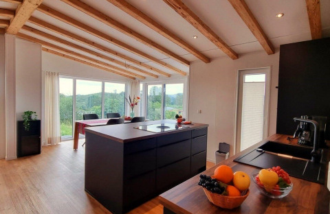 Modern kitchen and dining area in Chalet Enzian at Camping & Ferienpark Brilon, Germany, with scenic views.