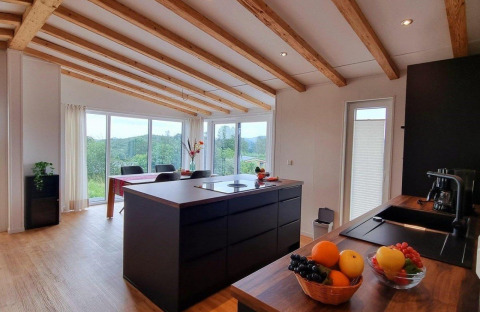 Modern kitchen and dining area in Chalet Enzian at Camping & Ferienpark Brilon, Germany, with scenic views.