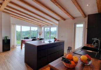 Modern kitchen and dining area in Chalet Enzian at Camping & Ferienpark Brilon, Germany, with scenic views.