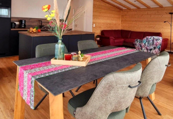 Eettafel met kleurrijke loper en vaas in moderne blokhut, Chalet Enzian, Camping & Ferienpark Brilon, Duitsland.